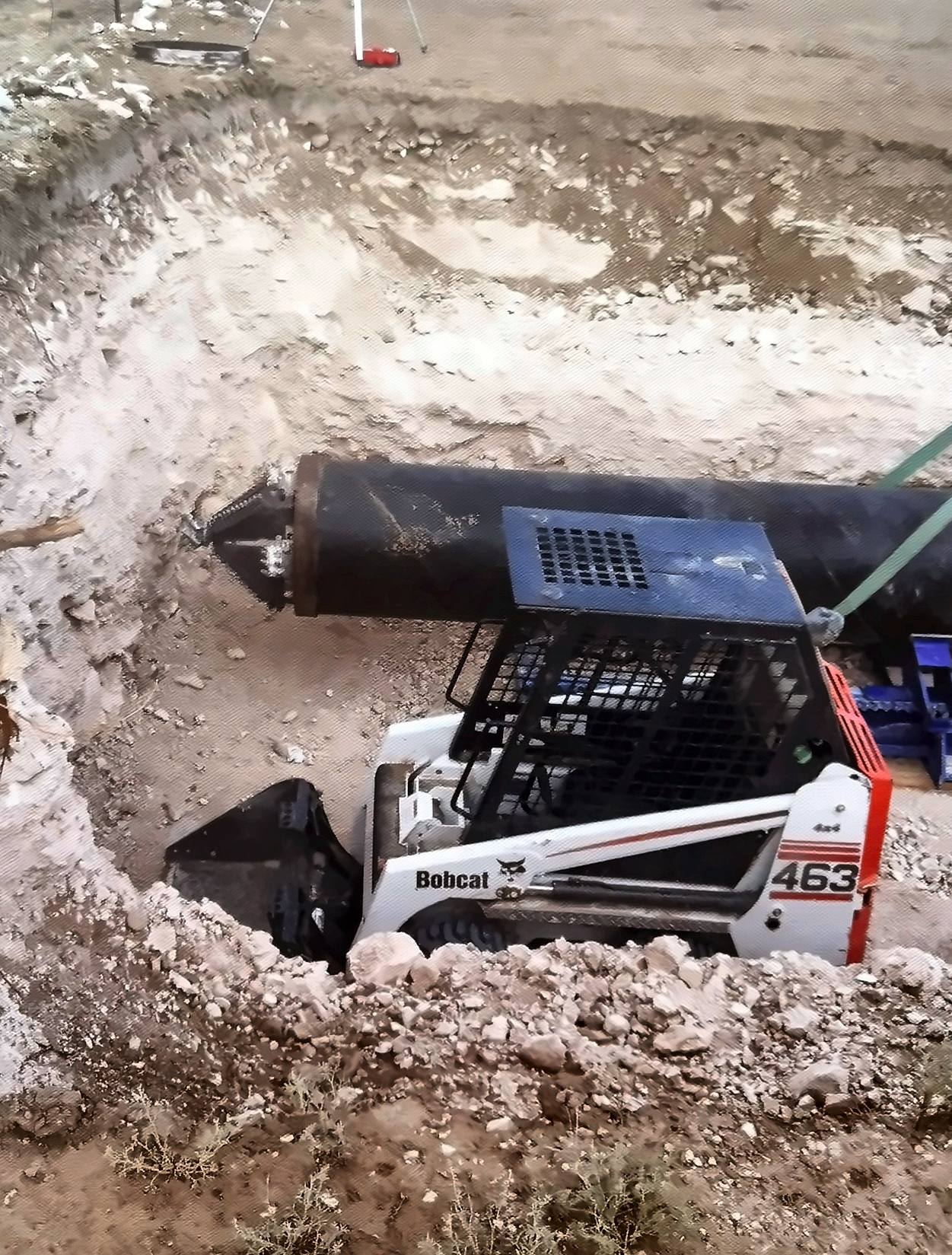 Bell hole excavation with a compact loader and steel pipe for a pipeline crossing